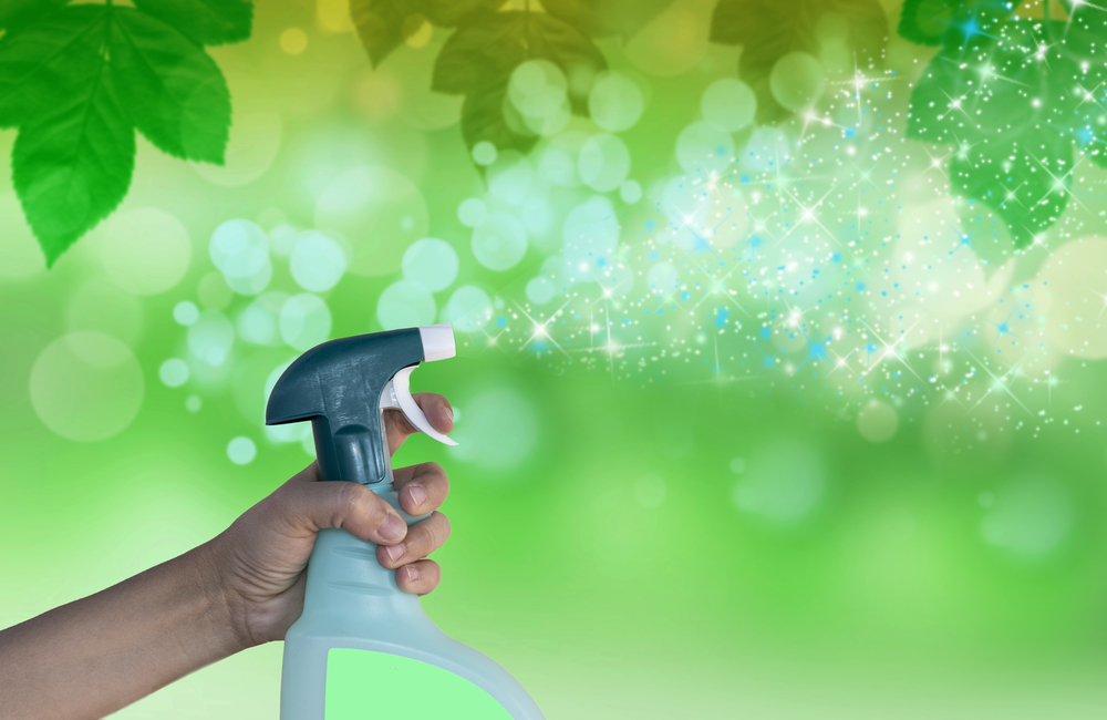GReen backdrop with hand spraying spray bottle using janitorial products to clean