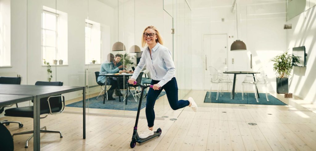 Office supply company having fun in the office with woman on a scooter