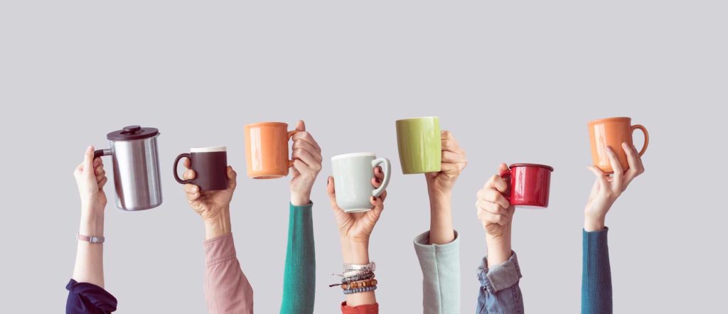 Office workers holding up colored coffee mugs