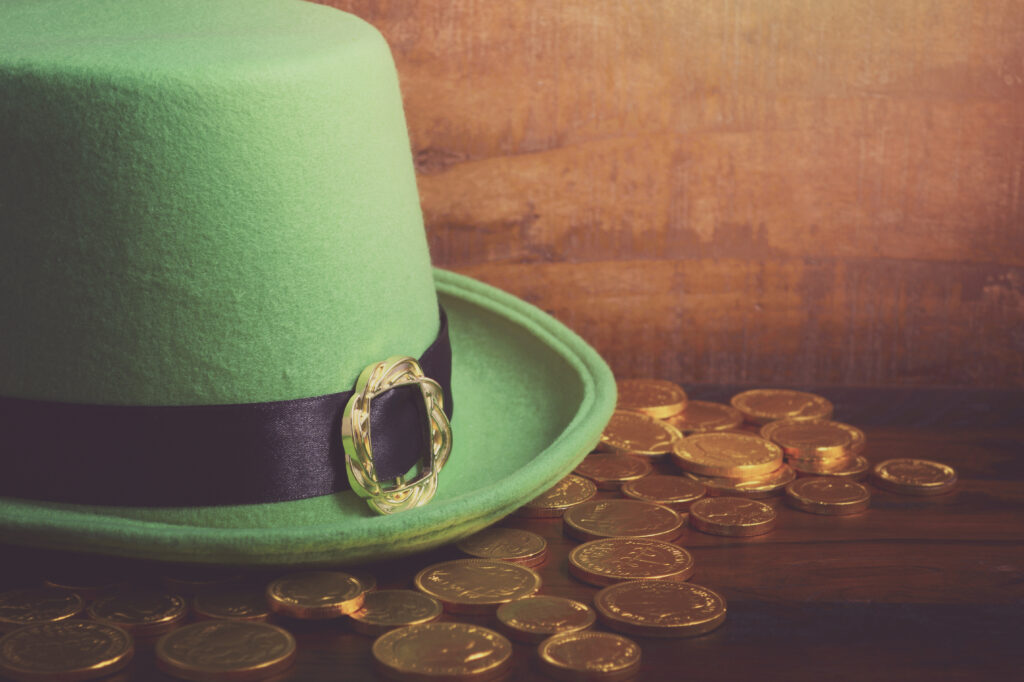 Irish top hat and gold coins spread out on a wooden table